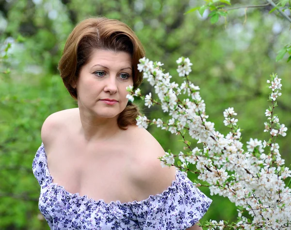 Mulher adulta perto das flores de cereja — Fotografia de Stock