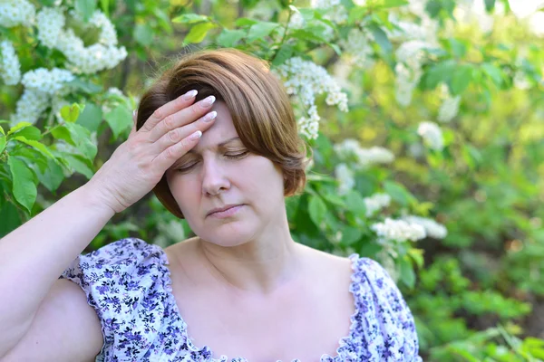 Доросла жінка з головним болем про цвітіння вишні навесні — стокове фото