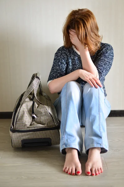 Traurige Frau sitzt wegen Scheidung mit Koffer an der Wand — Stockfoto