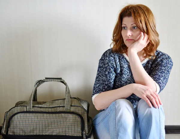 Mujer triste sentada cerca de la pared con la maleta porque el divorcio —  Fotos de Stock
