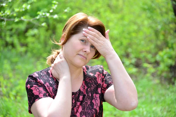 Mujer con dolor de cabeza y dolor de cuello en la naturaleza —  Fotos de Stock