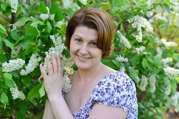 Adult woman near blossoming bird cherry in the park — Stock Photo, Image