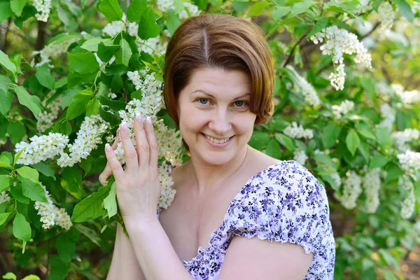 Adult woman near blossoming bird cherry in the park — Stock Photo, Image