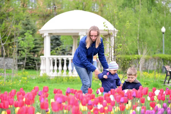 Mutter und Kinder entspannen sich im Blumenbeet — Stockfoto