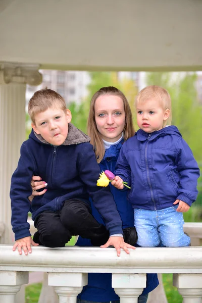 Matka s dvěma dětmi na procházce v altánu — Stock fotografie