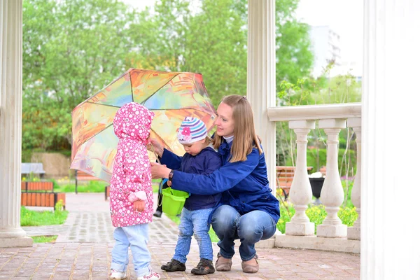 Madre con hijos y un paraguas en cenador —  Fotos de Stock