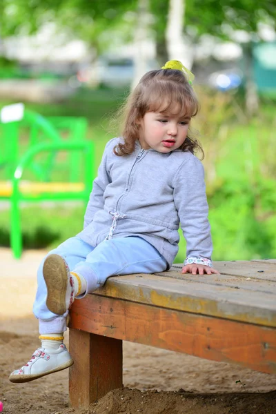 Двухлетняя девочка на скамейке в парке — стоковое фото