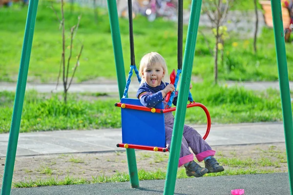 Маленькая девочка веселится на качелях на открытом воздухе — стоковое фото