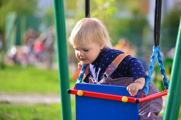 Liten flicka att ha kul på en gunga utomhus — Stockfoto