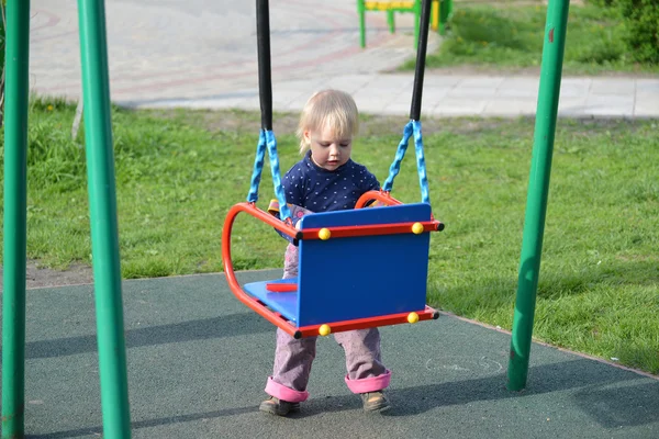 Liten flicka att ha kul på en gunga utomhus — Stockfoto