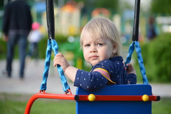 Liten flicka att ha kul på en gunga utomhus — Stockfoto