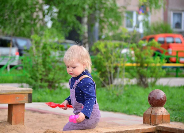 Klein meisje in de zandbak spelen — Stockfoto