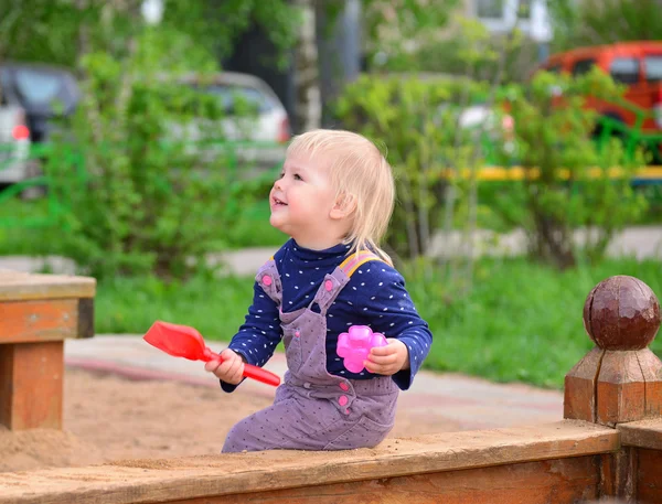 Klein meisje in de zandbak spelen — Stockfoto