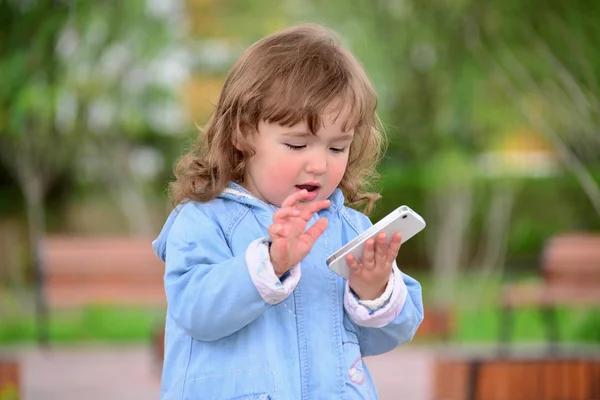 Chica de dos años, con un celular en el parque — Foto de Stock