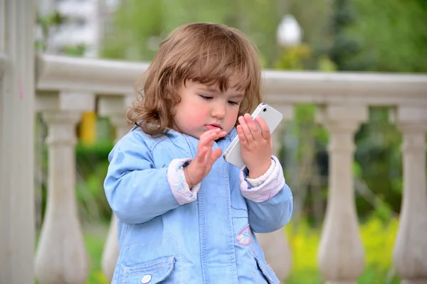 Chica de dos años, con un celular en el parque — Foto de Stock
