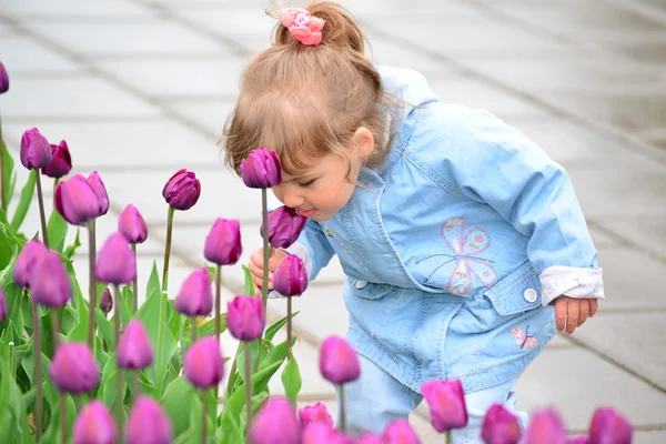 Niña cerca del macizo de flores con tulipanes — Foto de Stock