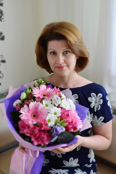 Woman with a bouquet of flowers in the room — Stock Photo, Image