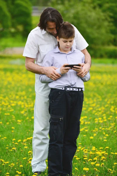 Apa és fia, és a telefon, a nyári park — Stock Fotó