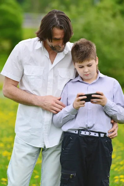 Apa és fia, és a telefon, a nyári park — Stock Fotó