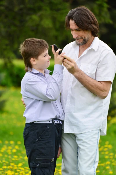 Father and son with a phone in  summer park — Stock Photo, Image