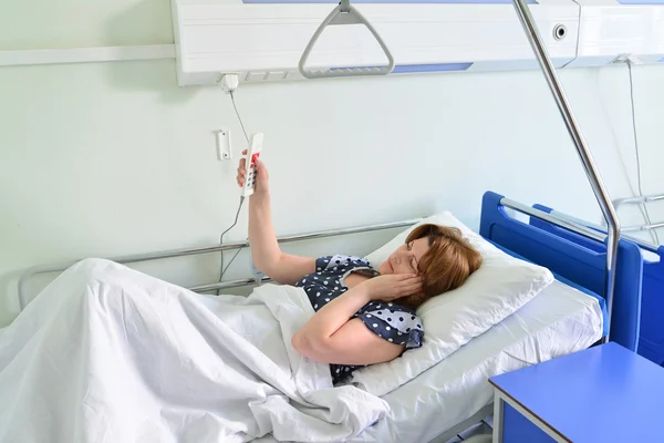 Paciente feminina Chame seu médico deitado na cama na enfermaria do hospital — Fotografia de Stock