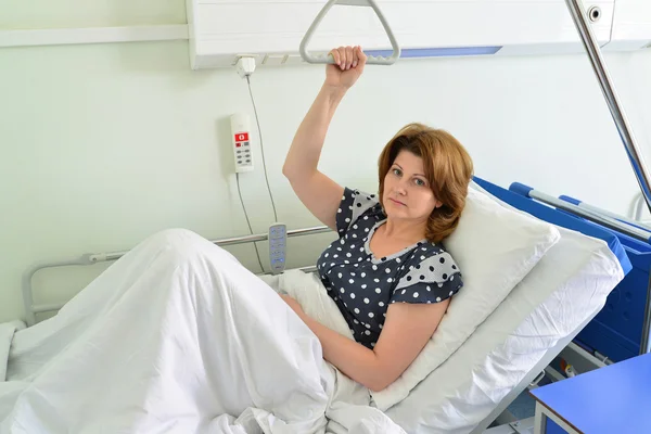 Paciente do sexo feminino segurando o dispositivo para elevação no quarto do hospital — Fotografia de Stock