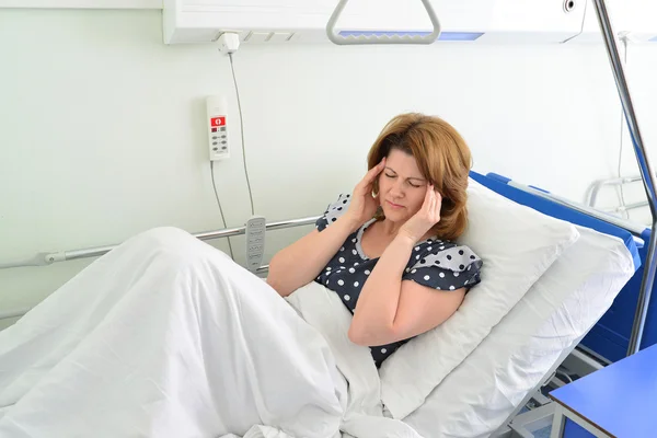 Vrouwelijke patiënt met hoofdpijn op bed in het ziekenhuis ward — Stockfoto