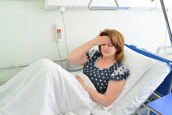 Female patient with headache on bed in hospital ward — Stock Photo, Image