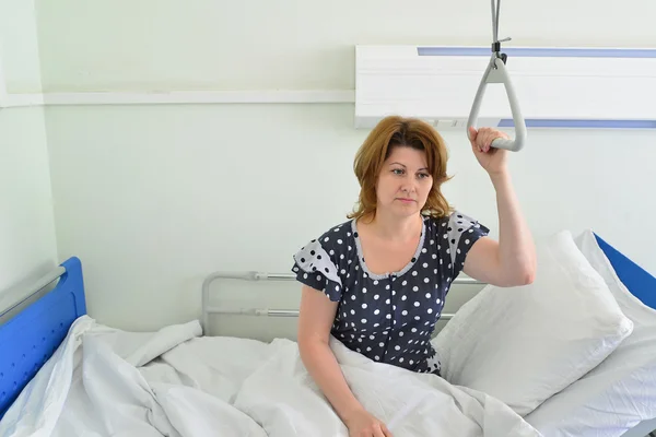 Female patient holding on to device for lifting in hospital room — Stock Photo, Image
