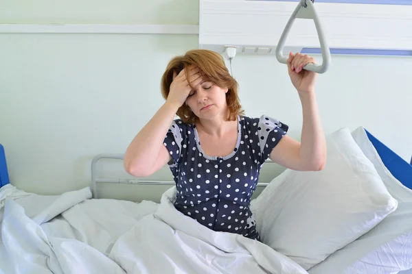 Female patient with headache on bed in hospital ward — Stock Photo, Image