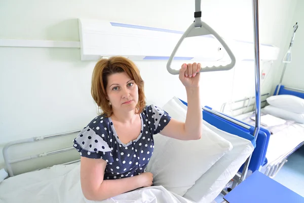 Female patient holding on to device for lifting in hospital room — Stock Photo, Image
