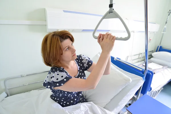 Paciente do sexo feminino segurando o dispositivo para elevação no quarto do hospital — Fotografia de Stock