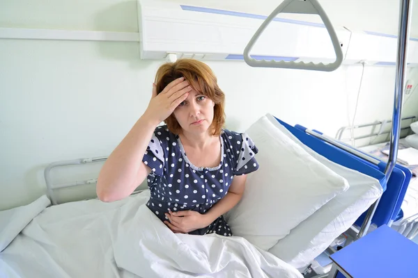 Female patient with headache on  bed in hospital ward — Stock Photo, Image