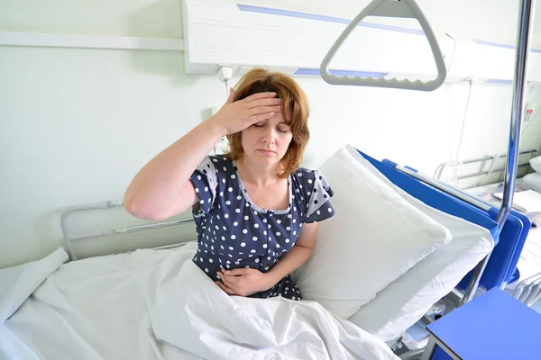 Female patient with headache on  bed in hospital ward — Stock Photo, Image