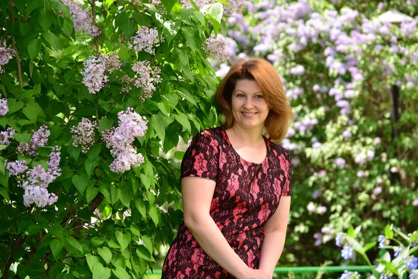 Middelbare leeftijd vrouw in de buurt van bloeiende lila — Stockfoto