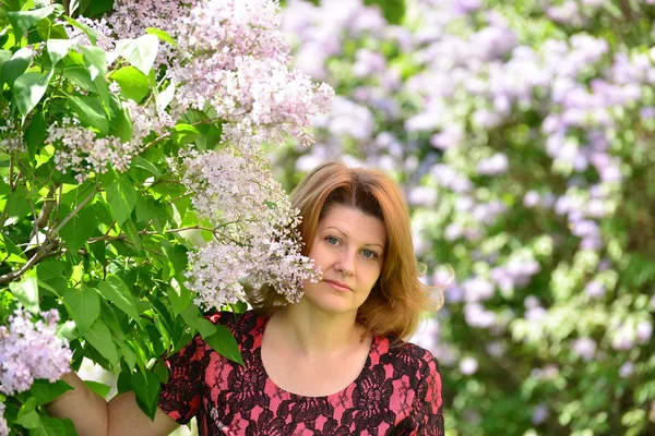 Donna di mezza età vicino alla fioritura lilla — Foto Stock