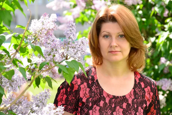 Donna di mezza età vicino alla fioritura lilla — Foto Stock