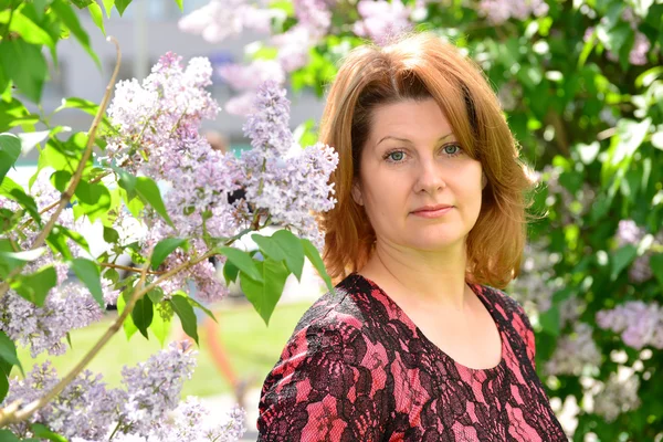 Middle-aged woman near blossoming lilac — Stock Photo, Image