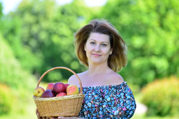 Donna adulta con un cesto di frutta nel parco — Foto Stock