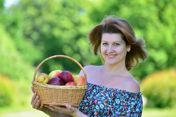 Доросла жінка з кошиком фруктів в парку — стокове фото