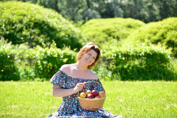 Donna adulta con un cesto di frutta nel parco — Foto Stock