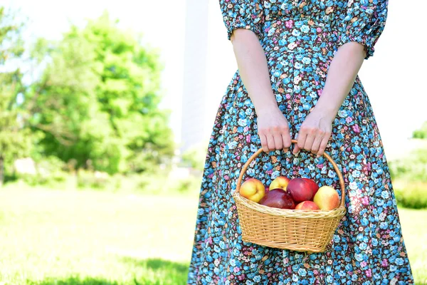 Femme adulte avec un panier de fruits dans le parc — Photo