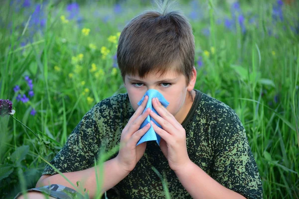 Teen boy with allergies in flowering herbs — Stock Photo, Image