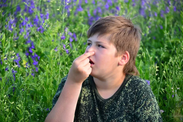 Teen boy with allergies in flowering herbs — Stock Photo, Image
