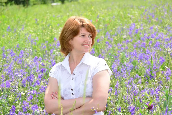 Mujer adulta en el prado con flores silvestres — Foto de Stock