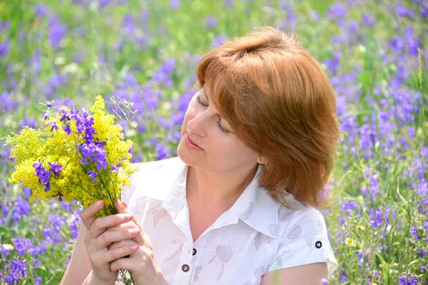 Donna adulta nel prato con fiori selvatici — Foto Stock