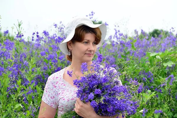 Femme avec un bouquet de fleurs sauvages sur la pelouse — Photo