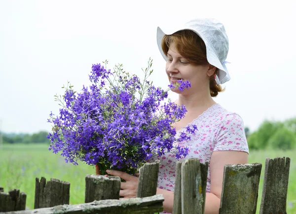 Femme aux fleurs sauvages près d'une clôture en bois dans le village — Photo