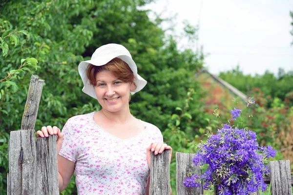 Femme aux fleurs sauvages près d'une clôture en bois dans le village — Photo