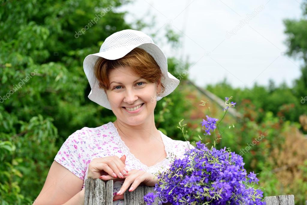 Woman with   wildflowers near  wooden fence in the village